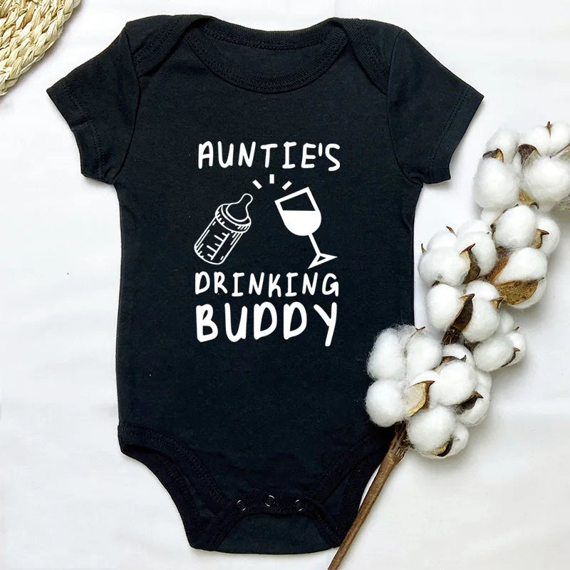 Black baby onesie with 'Auntie's Drinking Buddy' text on a white background with cotton and straw elements.