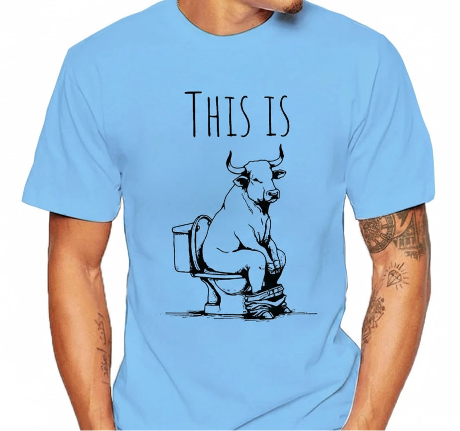 Light blue t-shirt with a graphic of a bull on a toilet and text 'THIS IS' worn by a person.