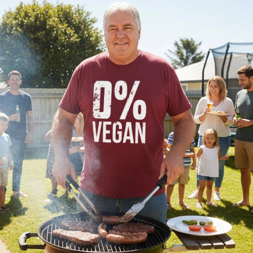 Man grilling burgers wearing a '0% Vegan' shirt in a backyard setting with family and friends.