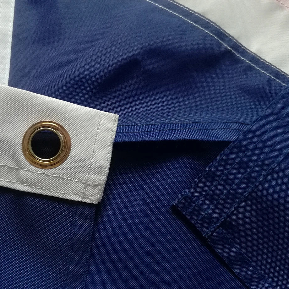 Close-up of a blue fabric with a white trim and gold button.