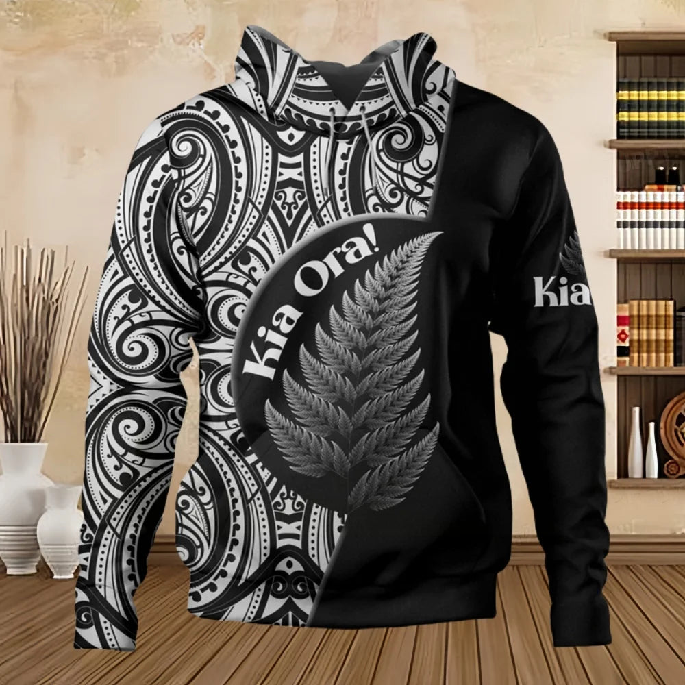 Black hoodie with white patterns and 'Kia Ora!' design on a wooden floor.