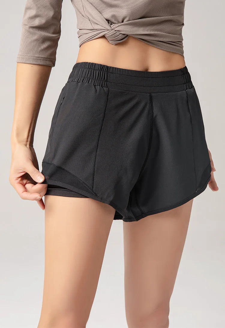 Black athletic shorts worn by a person on a plain background