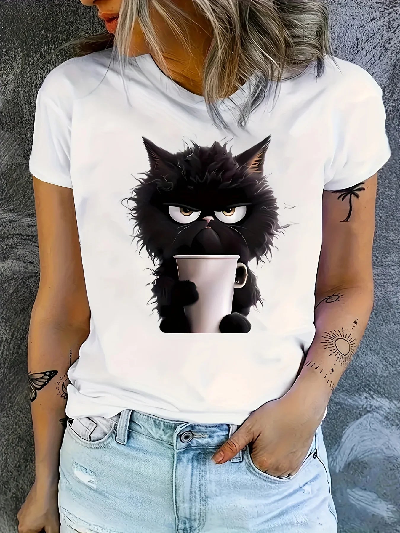 Person wearing a white t-shirt with a black cat holding a coffee cup design.