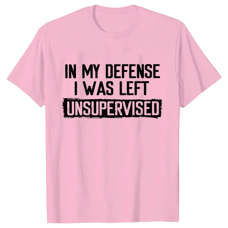 Pink t-shirt with black text 'IN MY DEFENSE I WAS LEFT UNSUPERVISED' on a white background