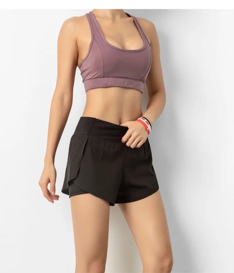 Person wearing a purple sports bra and black shorts on a light gray background