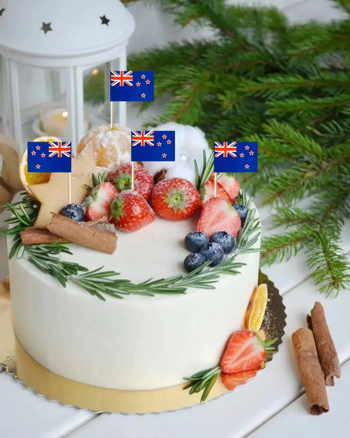 Decorative cake with fruit and flags on a white surface with greenery in the background